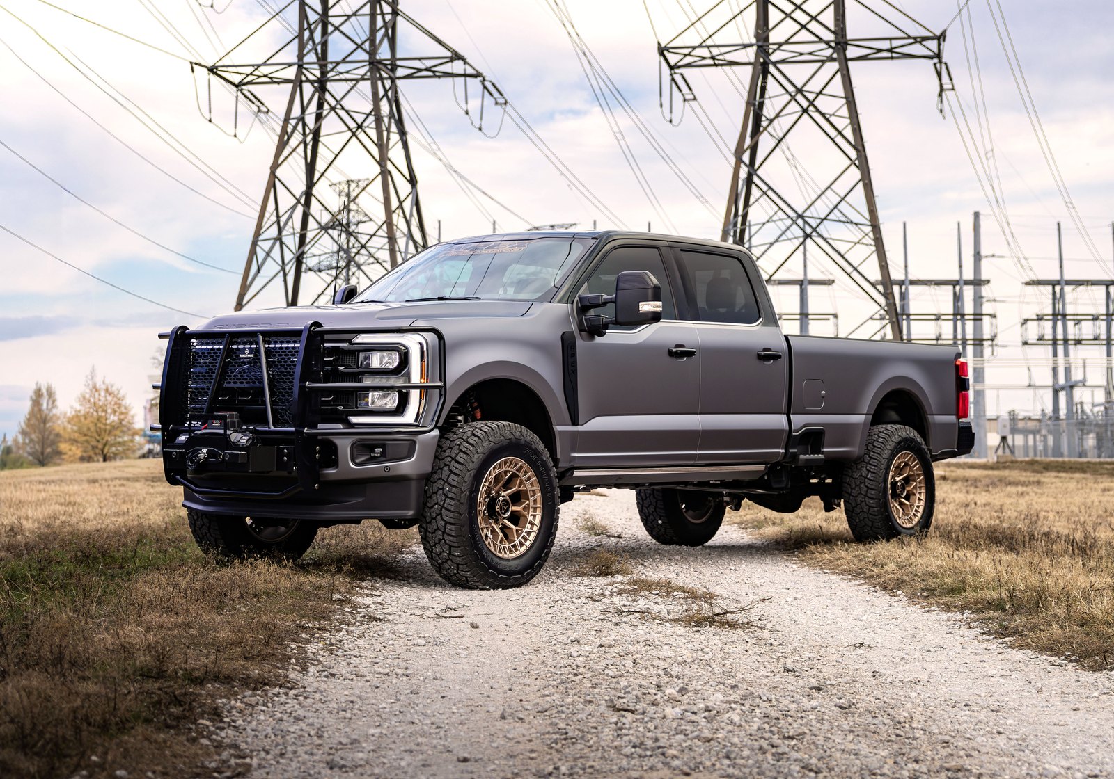 Lifted Ford F-350 on bronze wheels with a brush guard and winch, built by Apex Custom Innovations