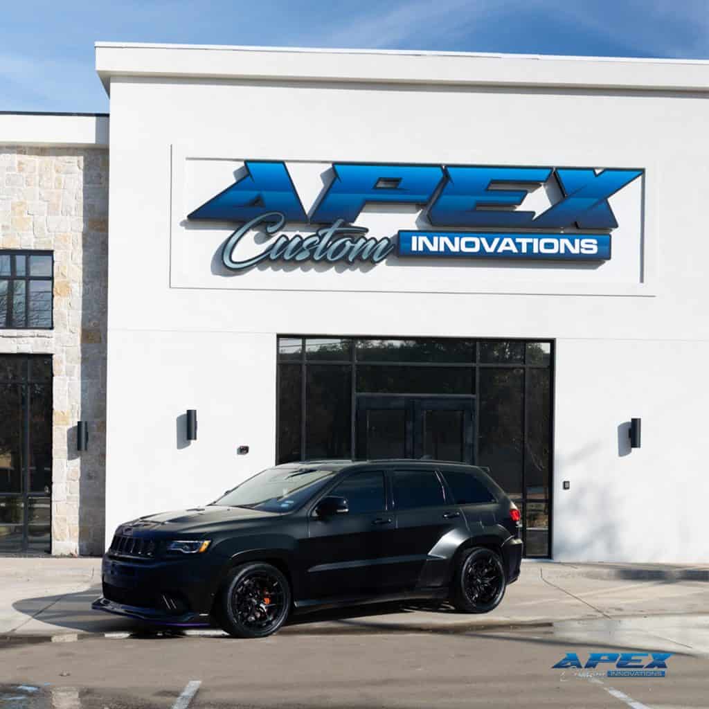 2018 Jeep Grand Cherokee Trackhawk with matte black vinyl wrap, Waido wide body kit, Vossen wheels, and Nitto tires outside Apex Custom Innovations