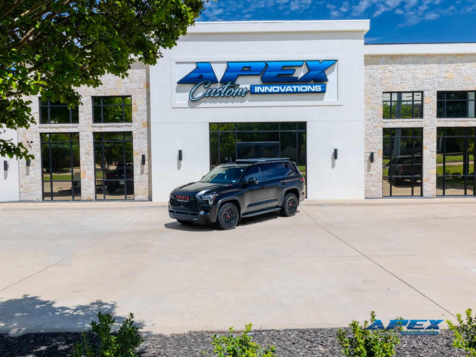 Wide exterior view of black 2024 Toyota Sequoia TRD Pro with satin black tuxedo wrap outside Apex Custom Innovations